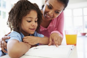 Mother Helping Daughter With Homework In Kitchen